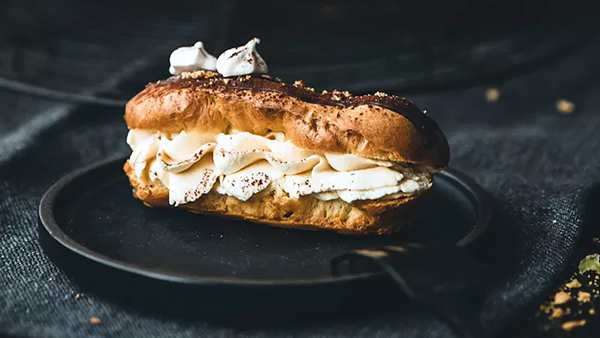 eclair mit schoko überzug und sahne füllung auf einem schwarzen teller zubereitet nach einem neff rezept