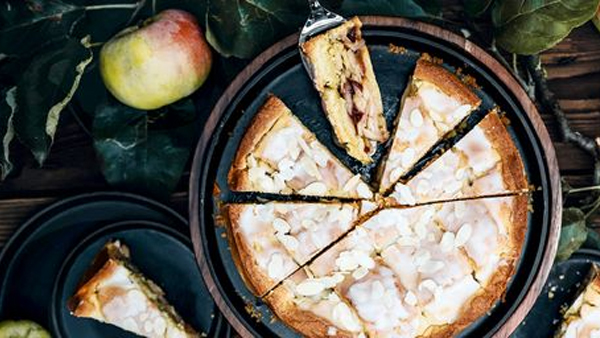 gedeckter apfelkuchen mit zuckerguss und mandeln