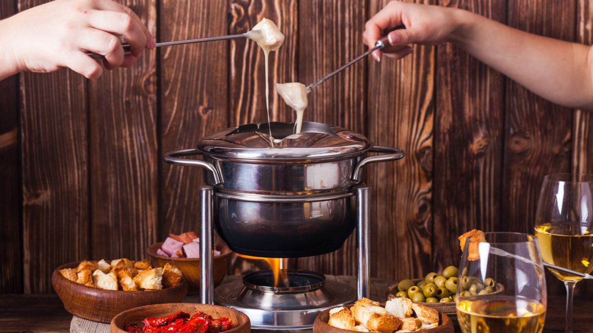 zwei personen tunken brot in ein käsefondue